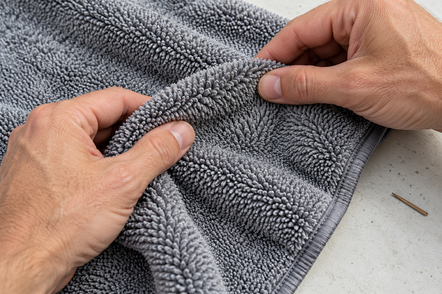 Hands parting microfibre towel pile to inspect its fibres and edge